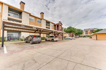 A parking lot with cars and a building in the background at Limestone Ranch Apartments, Lewisville 75067